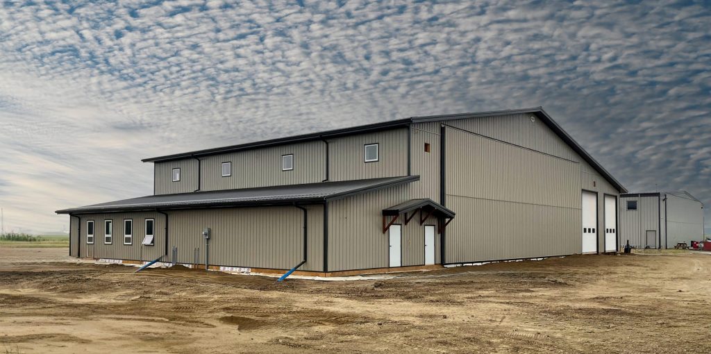 A hickory post-frame airplane hangar with 5 overhead doors and a bi-fold door