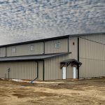 A hickory post-frame airplane hangar with 5 overhead doors and a bi-fold door