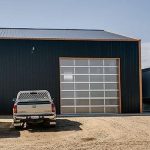 A copper penny agricultural post-frame shop with a bi-fold door
