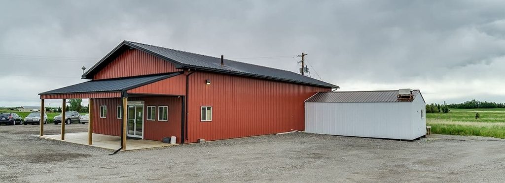 A tile red post-frame commercial build with one overhead door and soffits