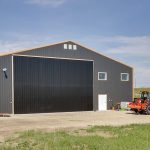 A copper penny agricultural post-frame shop with a bi-fold door