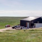 A copper penny agricultural post-frame shop with a bi-fold door