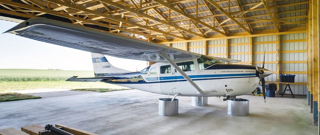 A turquoise post-frame airplane hangar with a bi-fold door