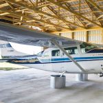 A turquoise post-frame airplane hangar with a bi-fold door