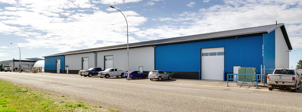 A white and blue post-frame commercial build with five overhead doors
