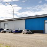 A white and blue post-frame commercial build with five overhead doors