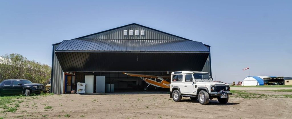 A sable post-frame airplane hangar with a bi-fold door