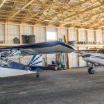 A sable post-frame airplane hangar with a bi-fold door