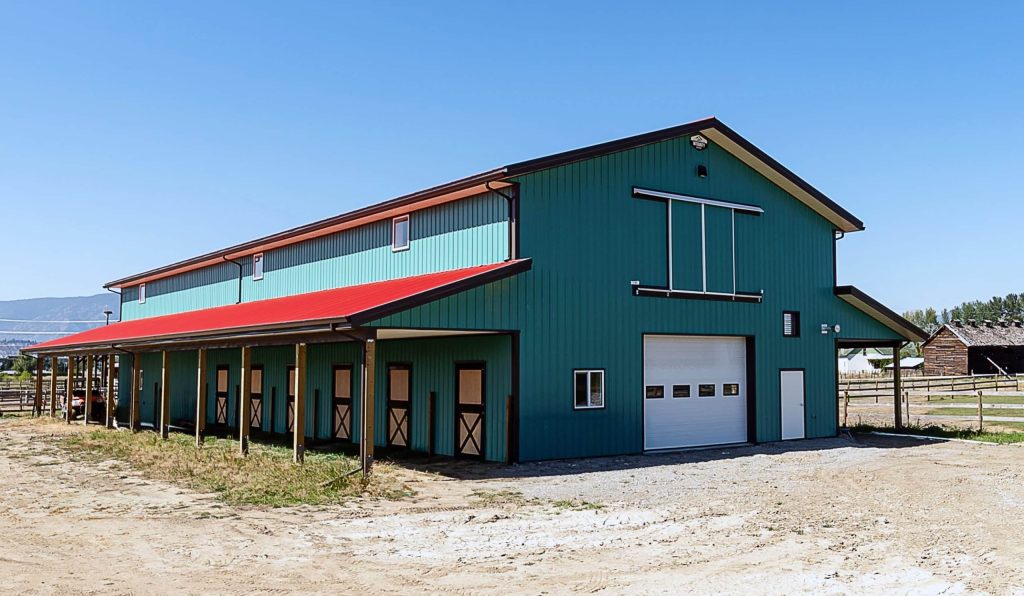 A turquoise post-frame equestrian barn