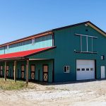 A turquoise post-frame equestrian barn