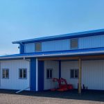 A bright white post-frame commercial building with two overhead doors