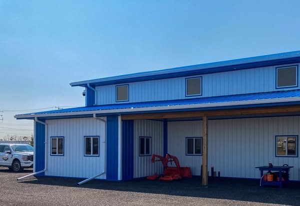 A bright white post-frame commercial building with two overhead doors