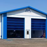 A bright white post-frame commercial building with two overhead doors