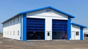 A bright white post-frame commercial building with two overhead doors