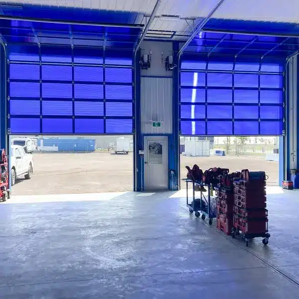 A bright white post-frame commercial building with two overhead doors