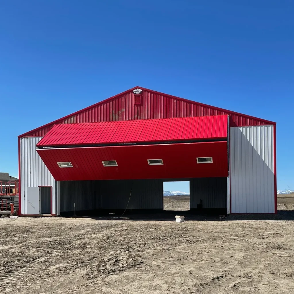 A bright white post-frame airplane hangar with a bright red bi-fold door and roof