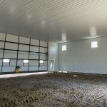 A bright white post-frame airplane hangar with a bright red bi-fold door and roof