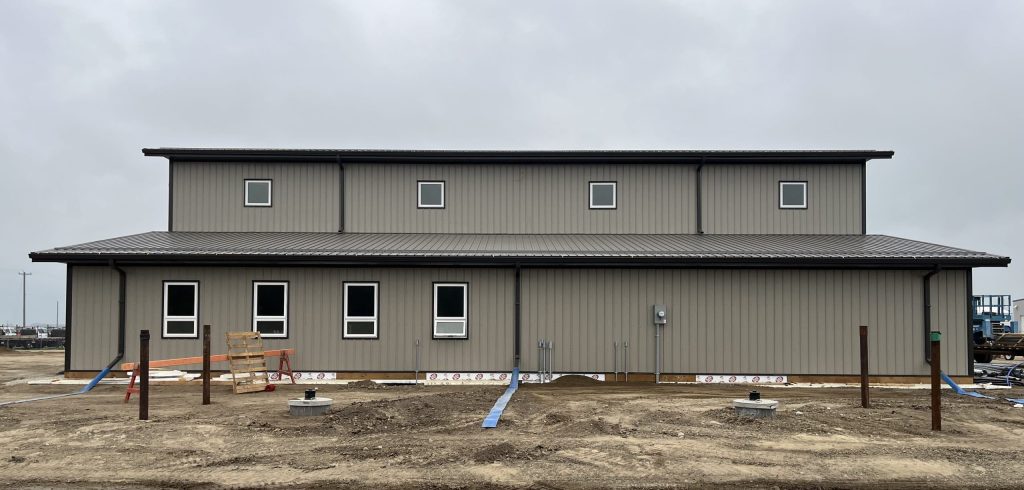 A hickory post-frame airplane hangar with 5 overhead doors and a bi-fold door