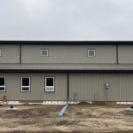A hickory post-frame airplane hangar with 5 overhead doors and a bi-fold door