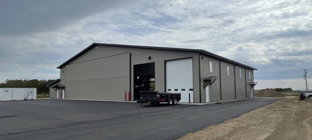 A hickory post-frame airplane hangar with 5 overhead doors and a bi-fold door