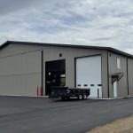 A hickory post-frame airplane hangar with 5 overhead doors and a bi-fold door
