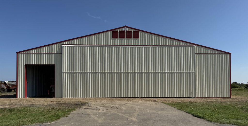 An antique linen post-frame airplane hangar with an overhead and bi-fold door