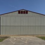 An antique linen post-frame airplane hangar with an overhead and bi-fold door