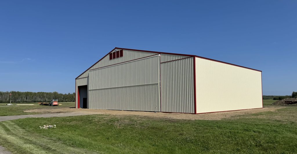 An antique linen post-frame airplane hangar with an overhead and bi-fold door