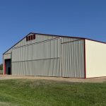 An antique linen post-frame airplane hangar with an overhead and bi-fold door