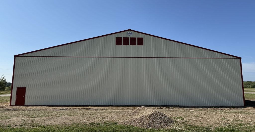 An antique linen post-frame airplane hangar with an overhead and bi-fold door