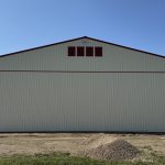 An antique linen post-frame airplane hangar with an overhead and bi-fold door