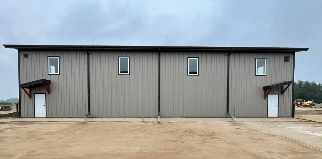 A hickory post-frame airplane hangar with 5 overhead doors and a bi-fold door