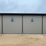 A hickory post-frame airplane hangar with 5 overhead doors and a bi-fold door