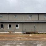 A hickory post-frame airplane hangar with 5 overhead doors and a bi-fold door