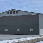 A regent grey post-frame airplane hangar with a bi-fold door