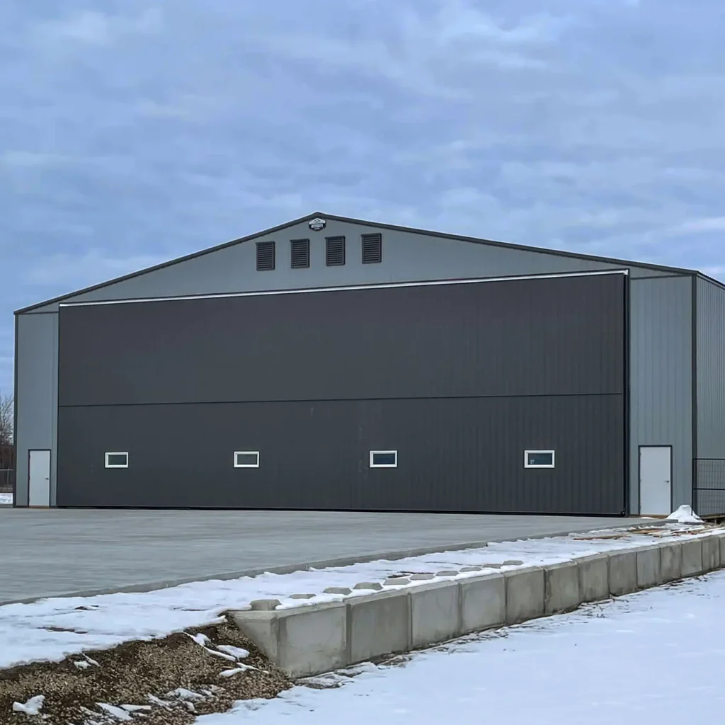 A regent grey post-frame airplane hangar with a bi-fold door
