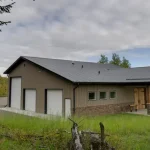 A buckskin post-frame equestrian barn
