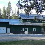 A post-frame melchers green residential barndominium with an attached garage