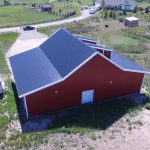 A bright red equestrian post-frame barn with an overhead door