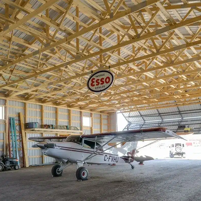A sable post-frame airplane hangar with a bi-fold door