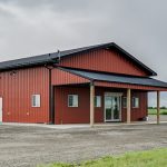 A tile red post-frame commercial build with one overhead door and soffits