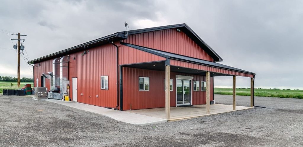 A tile red post-frame commercial build with one overhead door and soffits