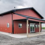 A tile red post-frame commercial build with one overhead door and soffits