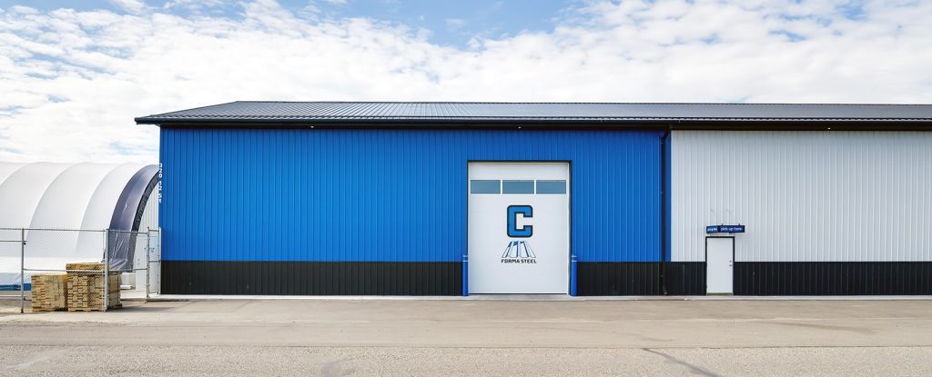 A white and blue post-frame commercial build with five overhead doors
