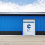 A white and blue post-frame commercial build with five overhead doors