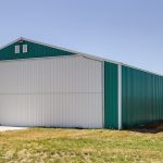 A turquoise post-frame airplane hangar with a bi-fold door