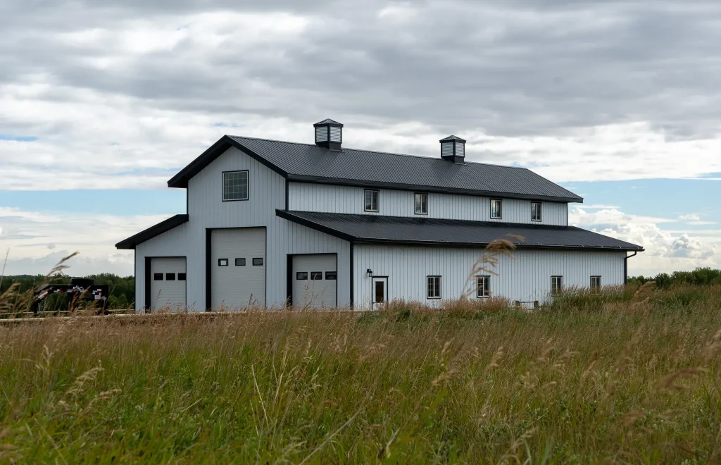 A bright white post-frame equestrian barn