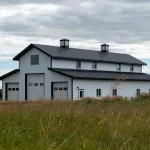 A bright white post-frame equestrian barn