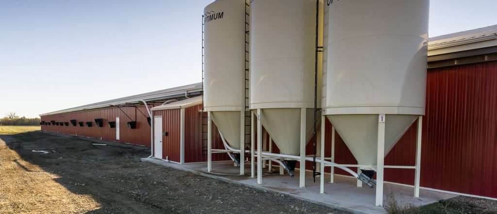 A dark red post-frame equestrian barn with four overhead and four bi-fold doors