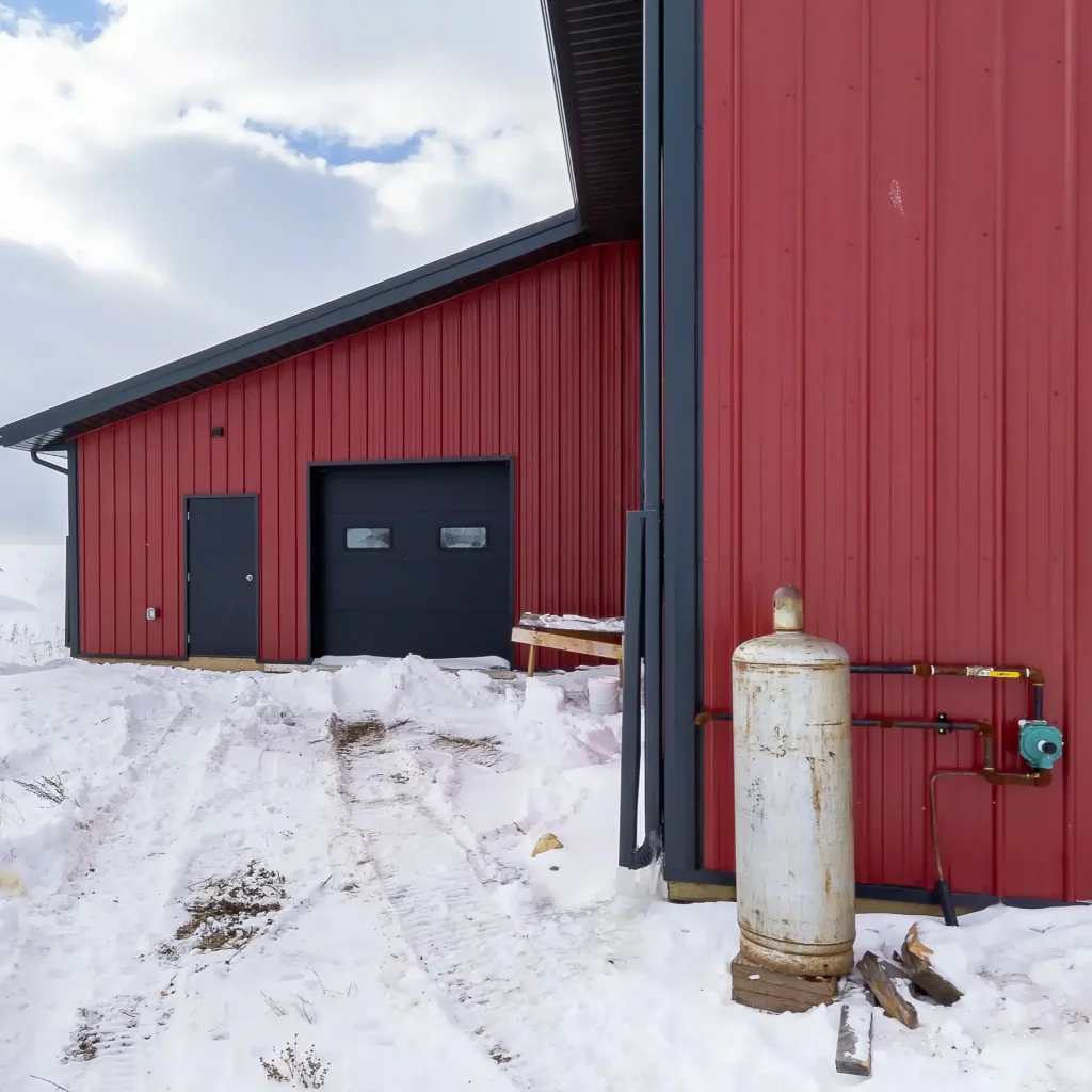 A dark red post-frame agricultural shop